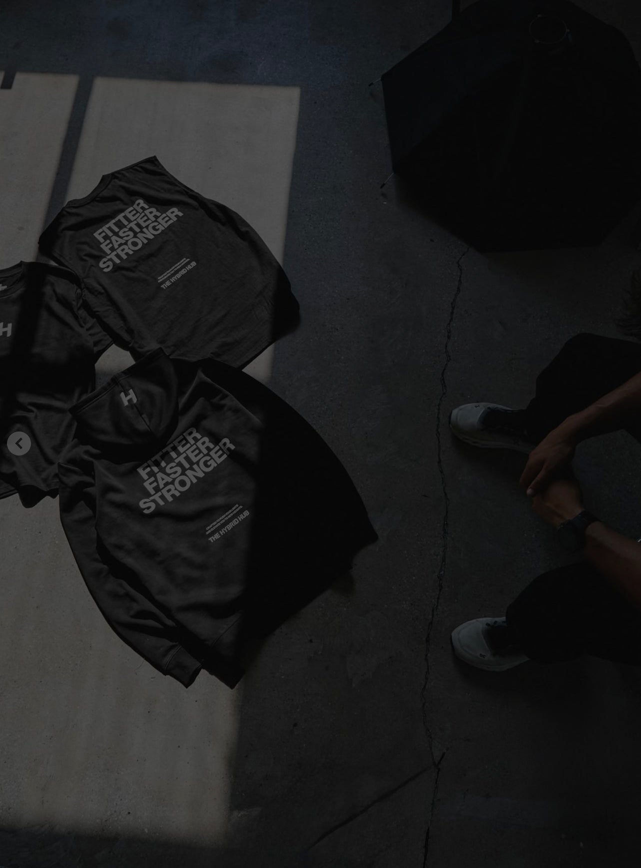 Black gym bag with 'Fitter Stronger' branding on a concrete floor.