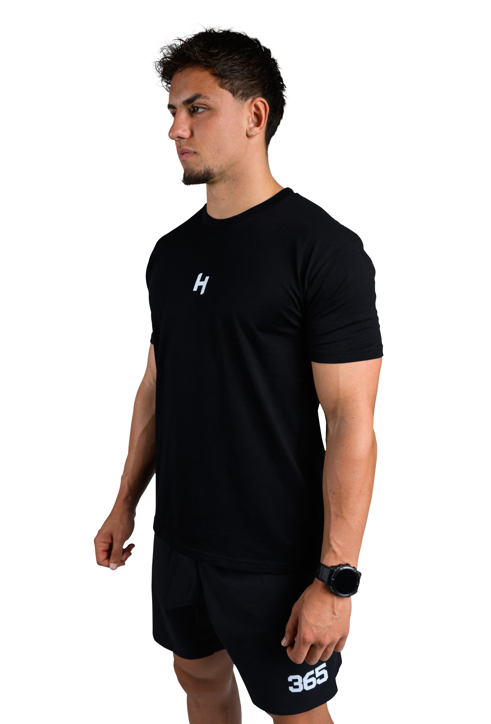 Man wearing a black t-shirt with a logo and black shorts on a white background