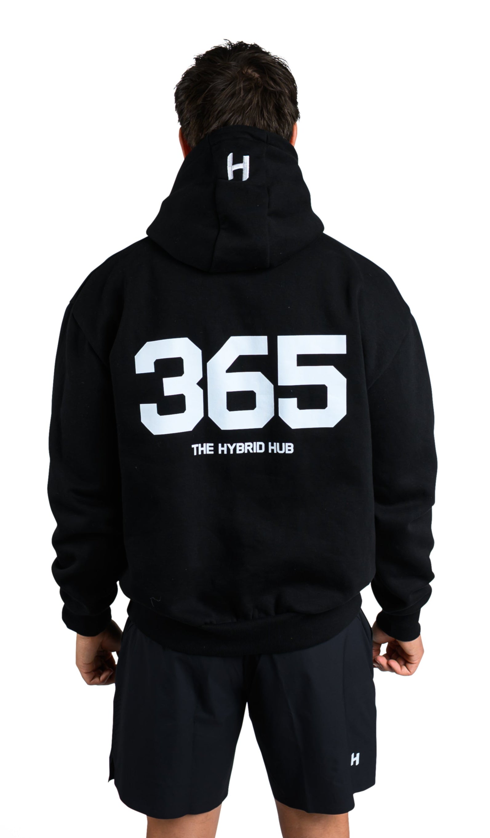 Person wearing a black hoodie with '365' and shorts on a white background