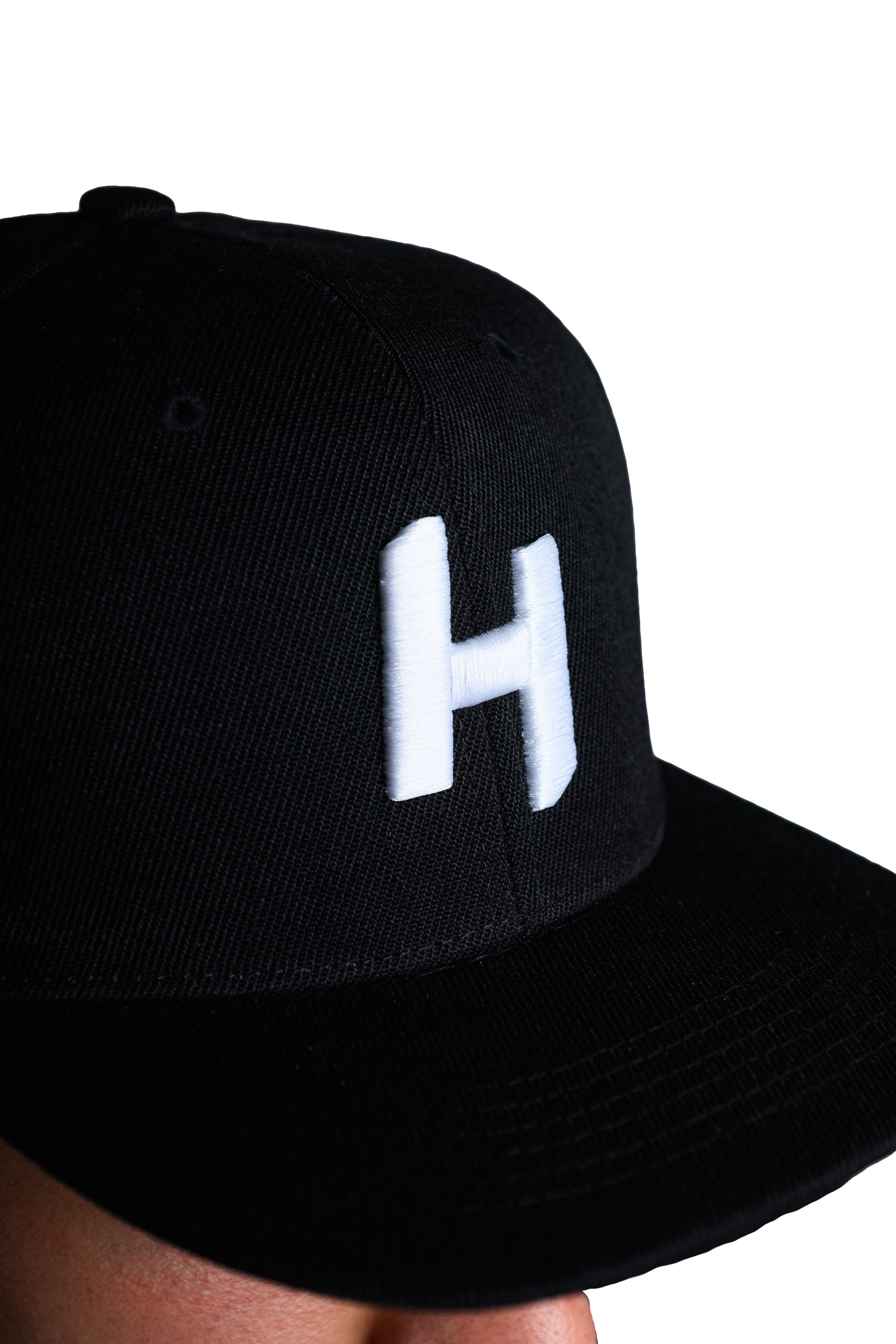 Black cap with a white 'H' logo on a white background