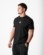 Man wearing a black t-shirt with a logo on a white background