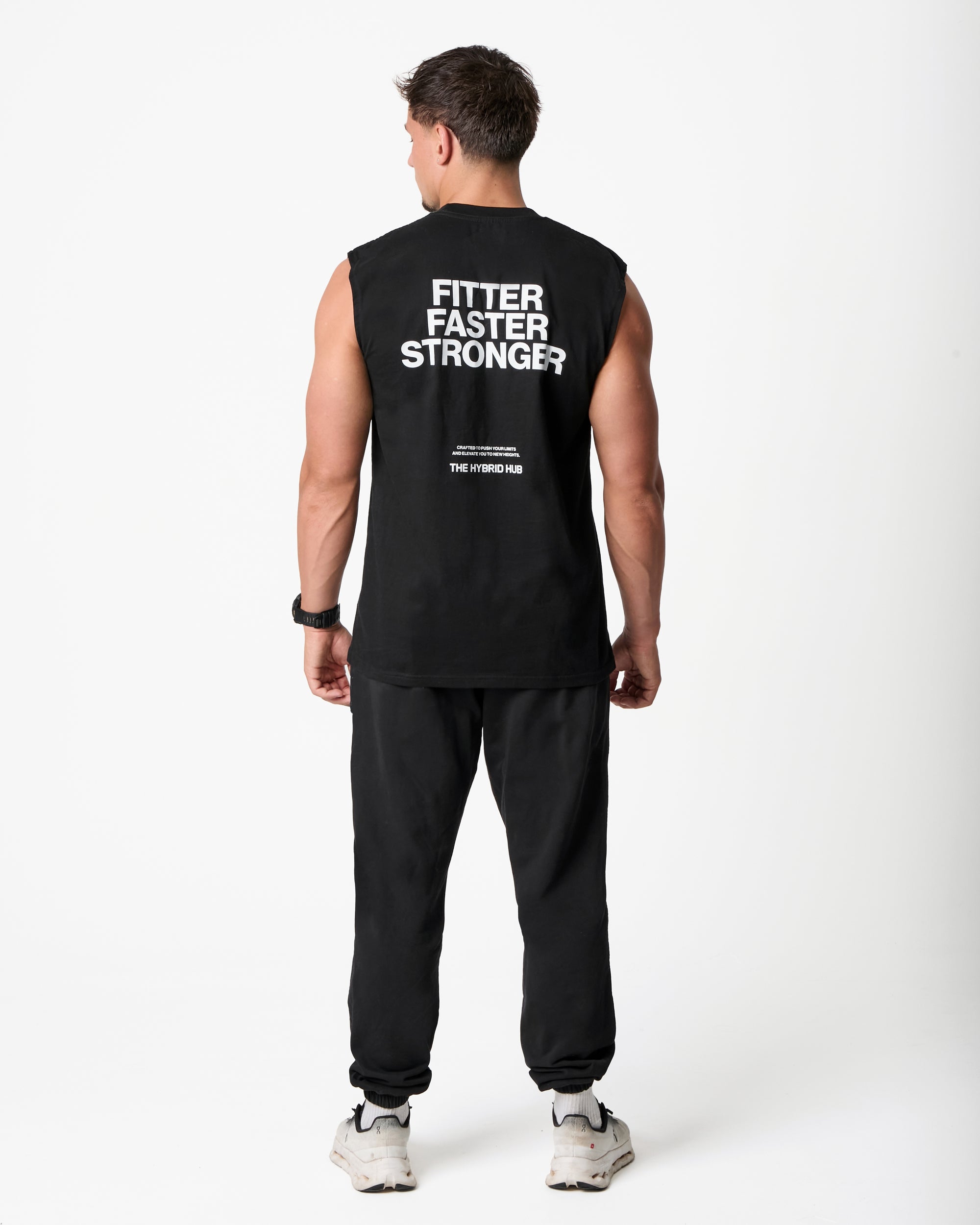 Person wearing a black sleeveless shirt with text on the back, standing against a white background