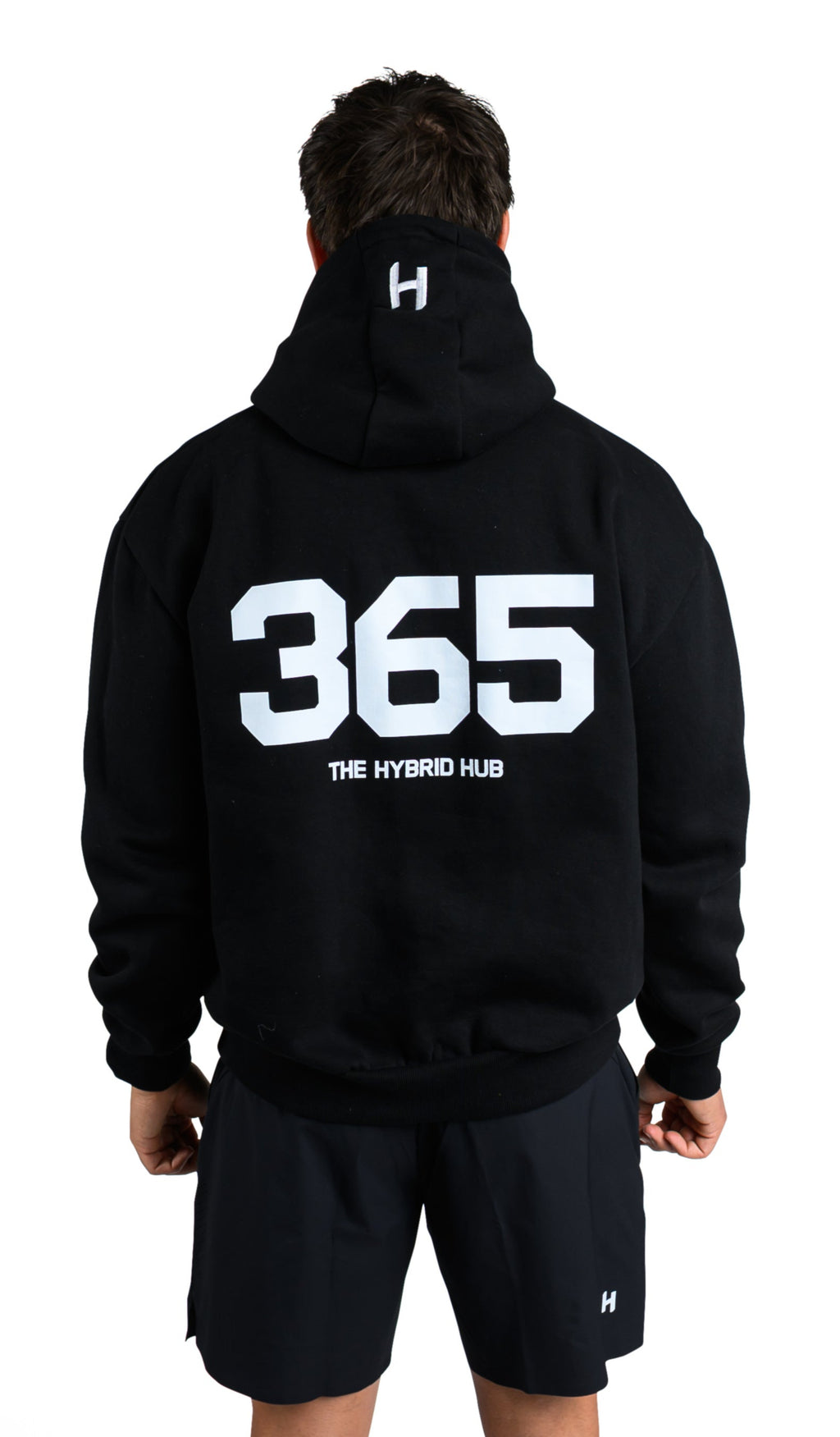 Person wearing a black hoodie with '365' and shorts on a white background