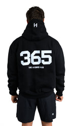 Person wearing a black hoodie with '365' and shorts on a white background