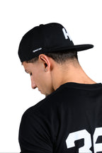 Person wearing a black t-shirt with '365' printed on the back against a white background